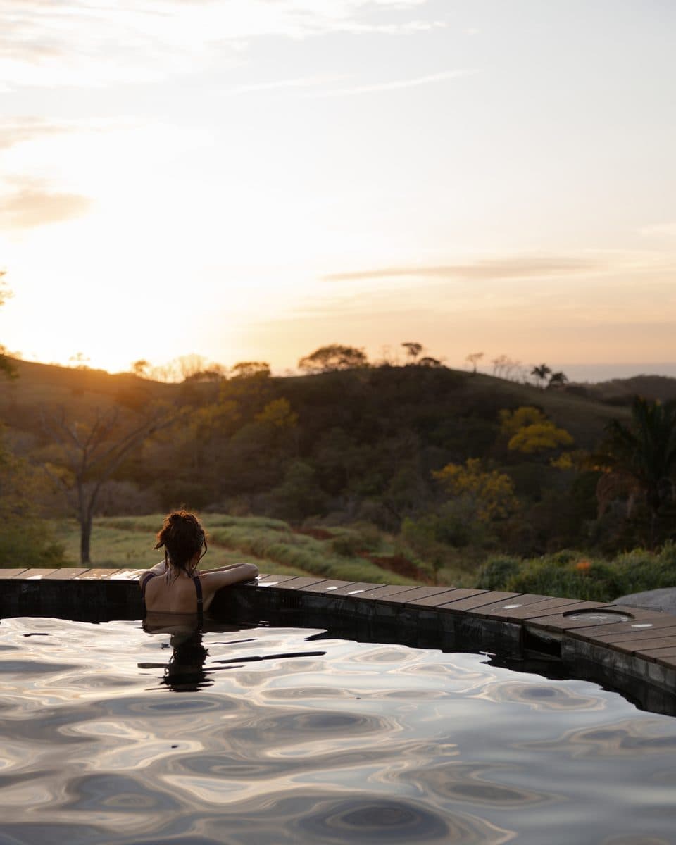 A figure looking out over the hills at sunset from a pool
