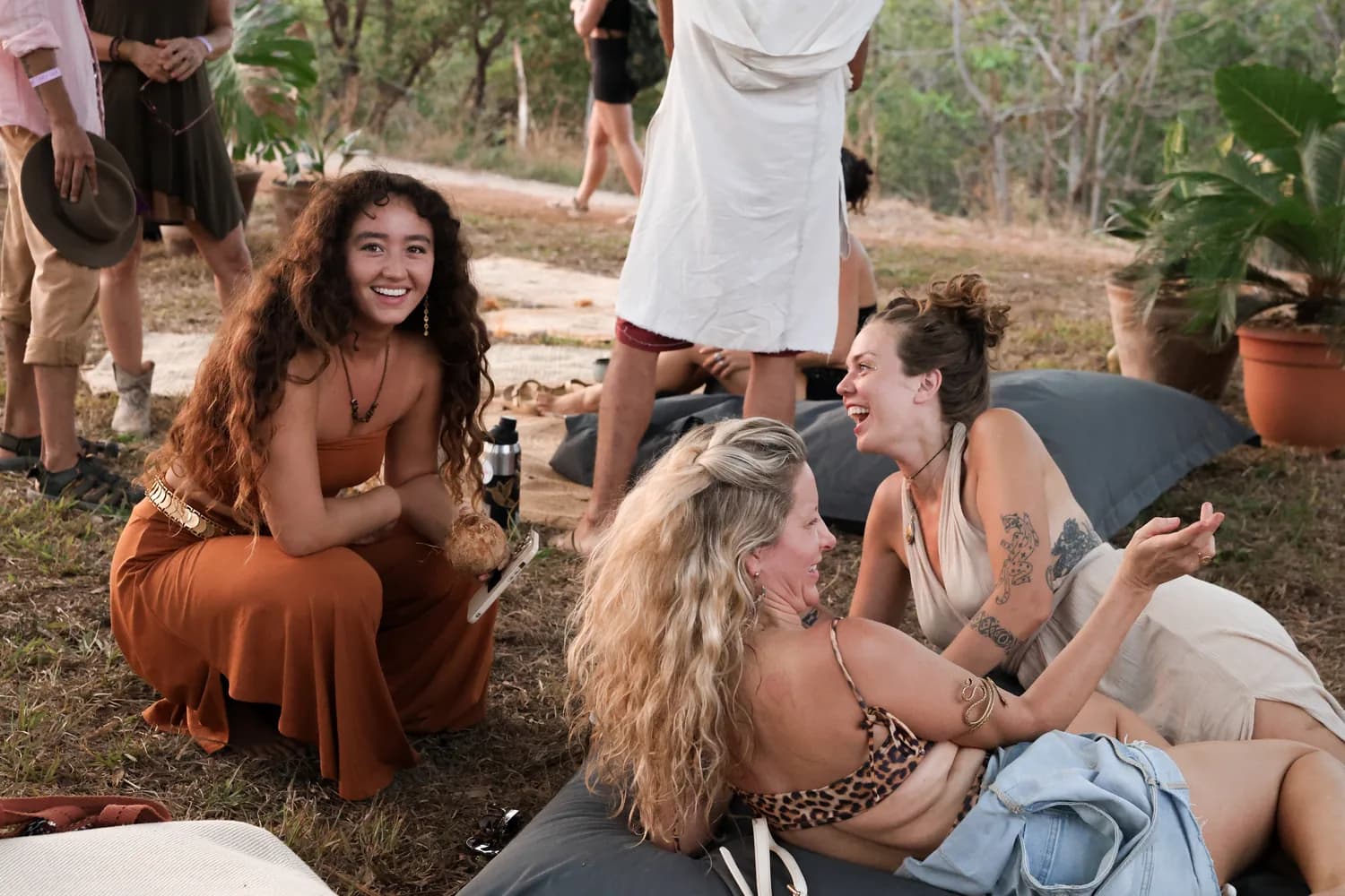 Residents laughing together on floor cushions outdoors at golden hour