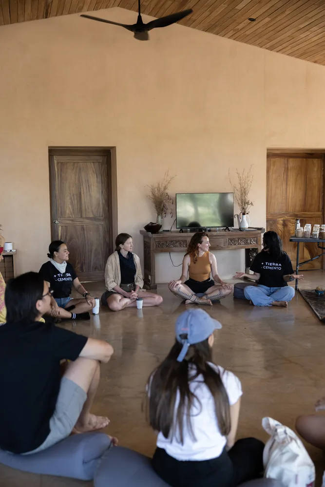 A circle of residents seated on the floor of a high-ceilinged open room