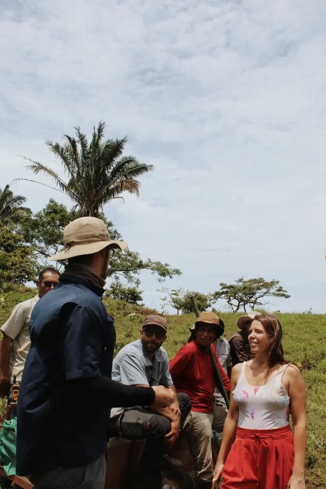Residents and farm crew gathered on a grassy hillside during a tree planting day