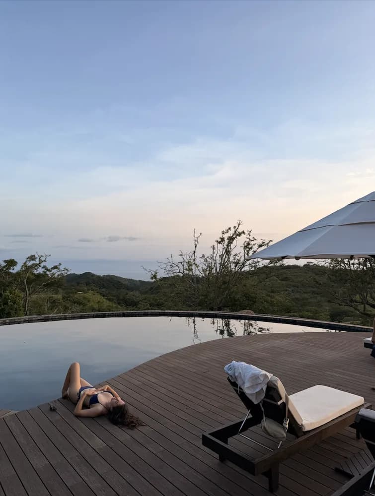 Someone lying on the pool deck at dusk, the valley beyond