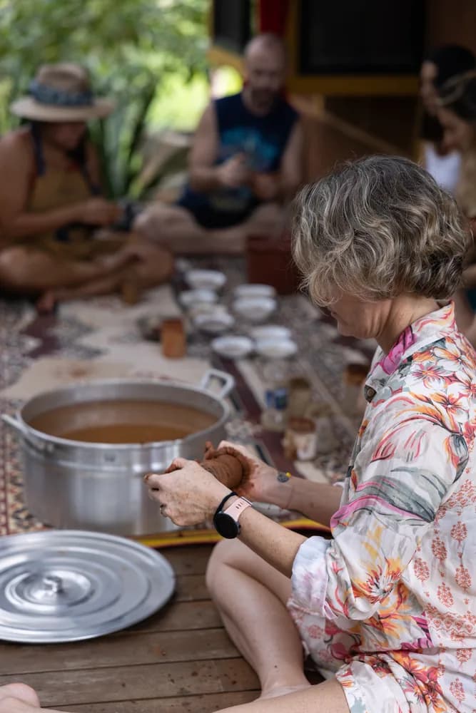 Residents sitting on rugs around a large pot, cups set out along the mat