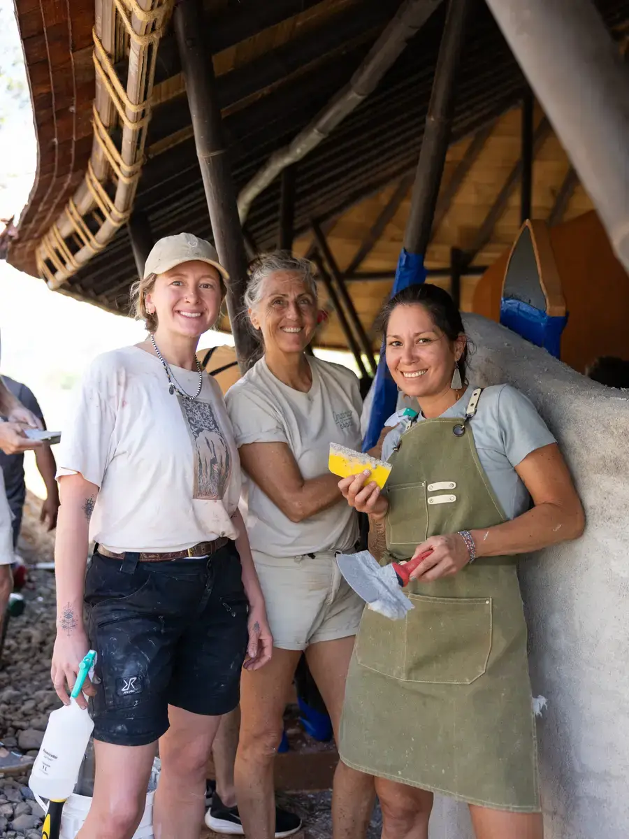Three people in aprons, hands and clothes marked with lime plaster