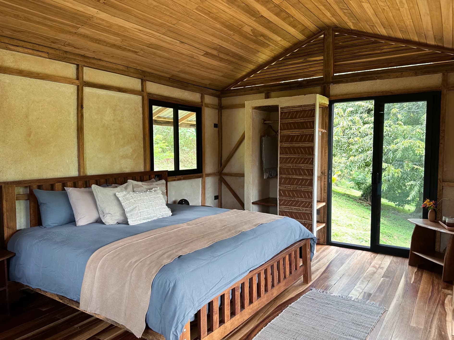 A private casita with a double bed, clay walls and glass doors opening onto the garden